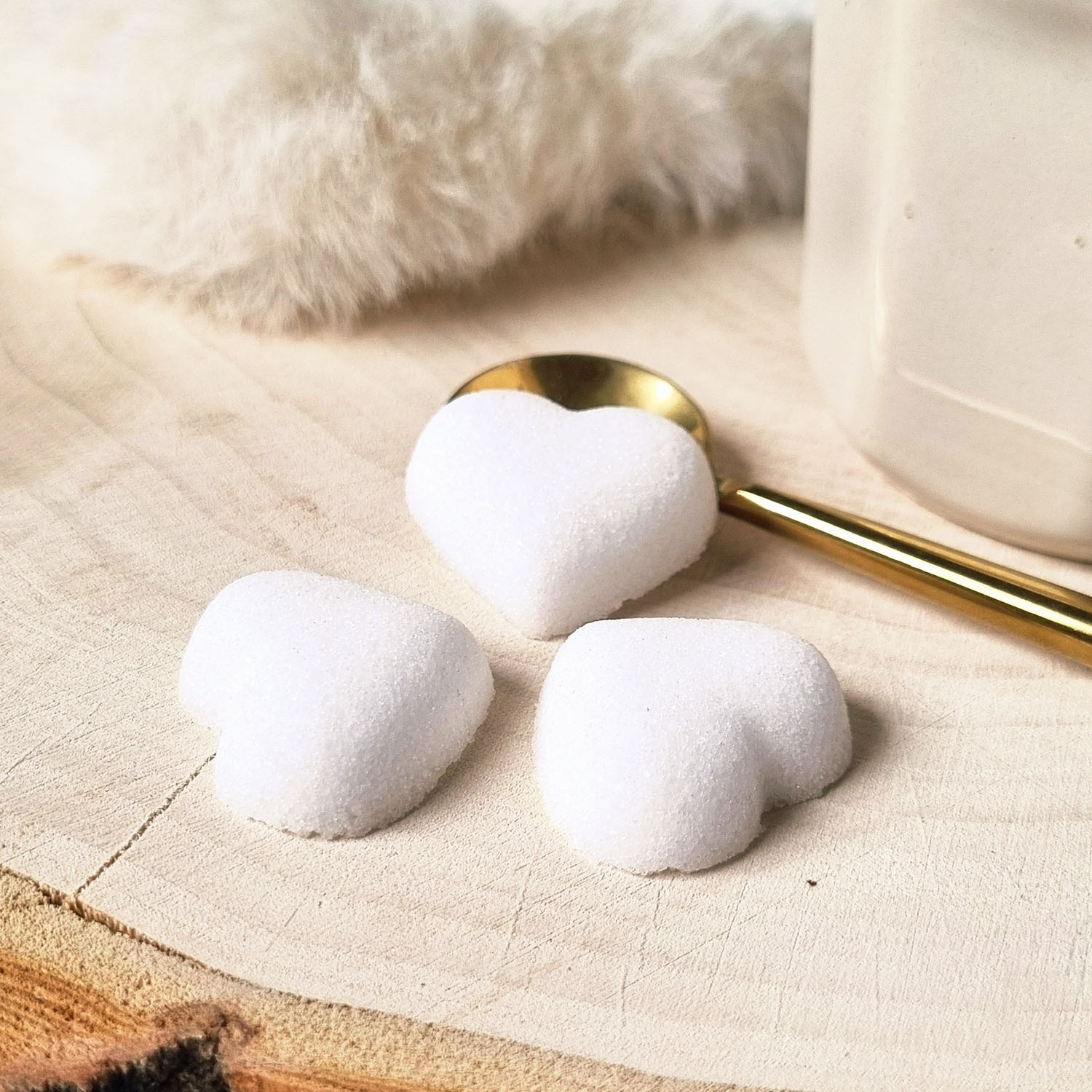 sucres en forme de coeurs blancs - cuillère dorée - tasse - fourrure et bois