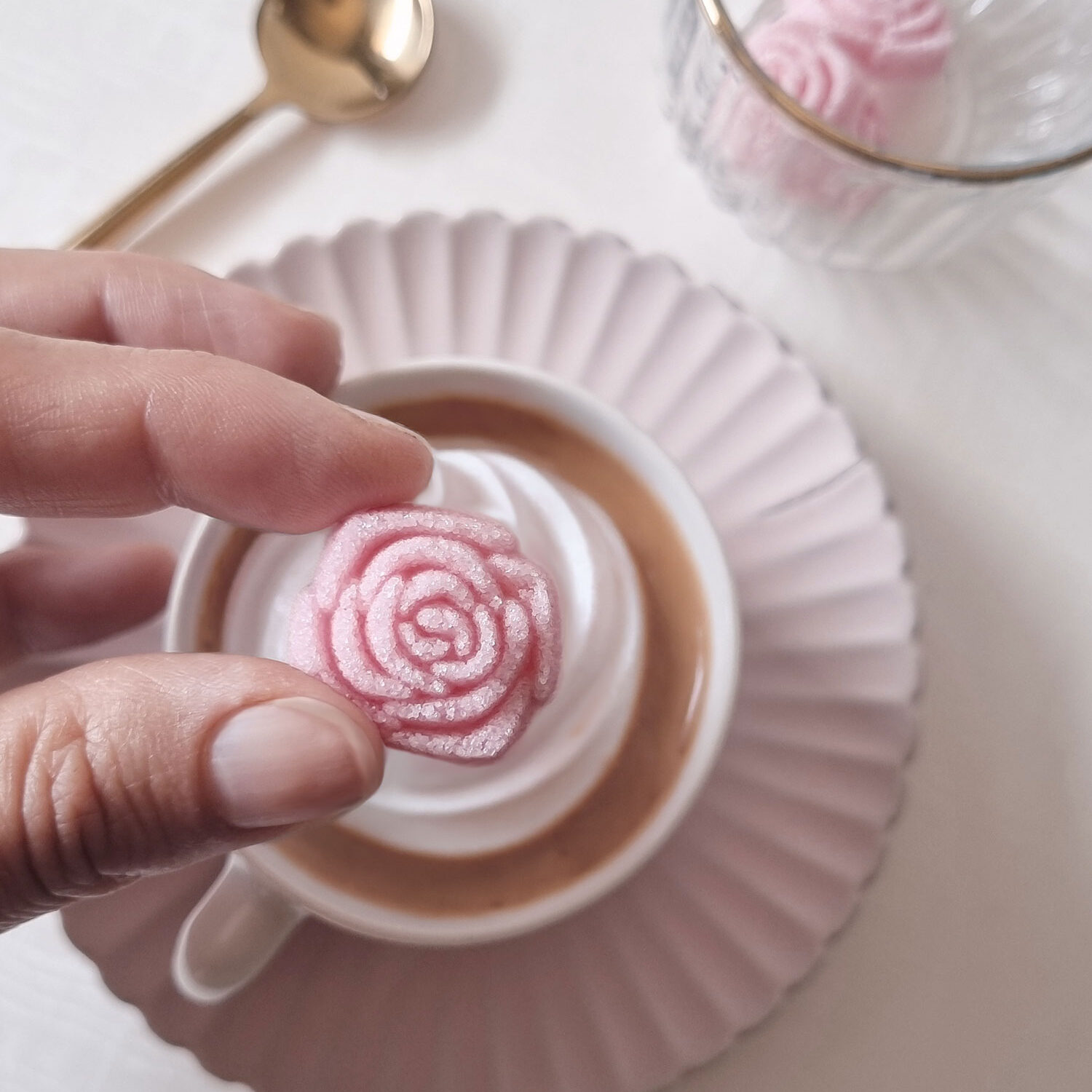 un sucre coloré en rose, en forme de fleur, pour sucrer un café
